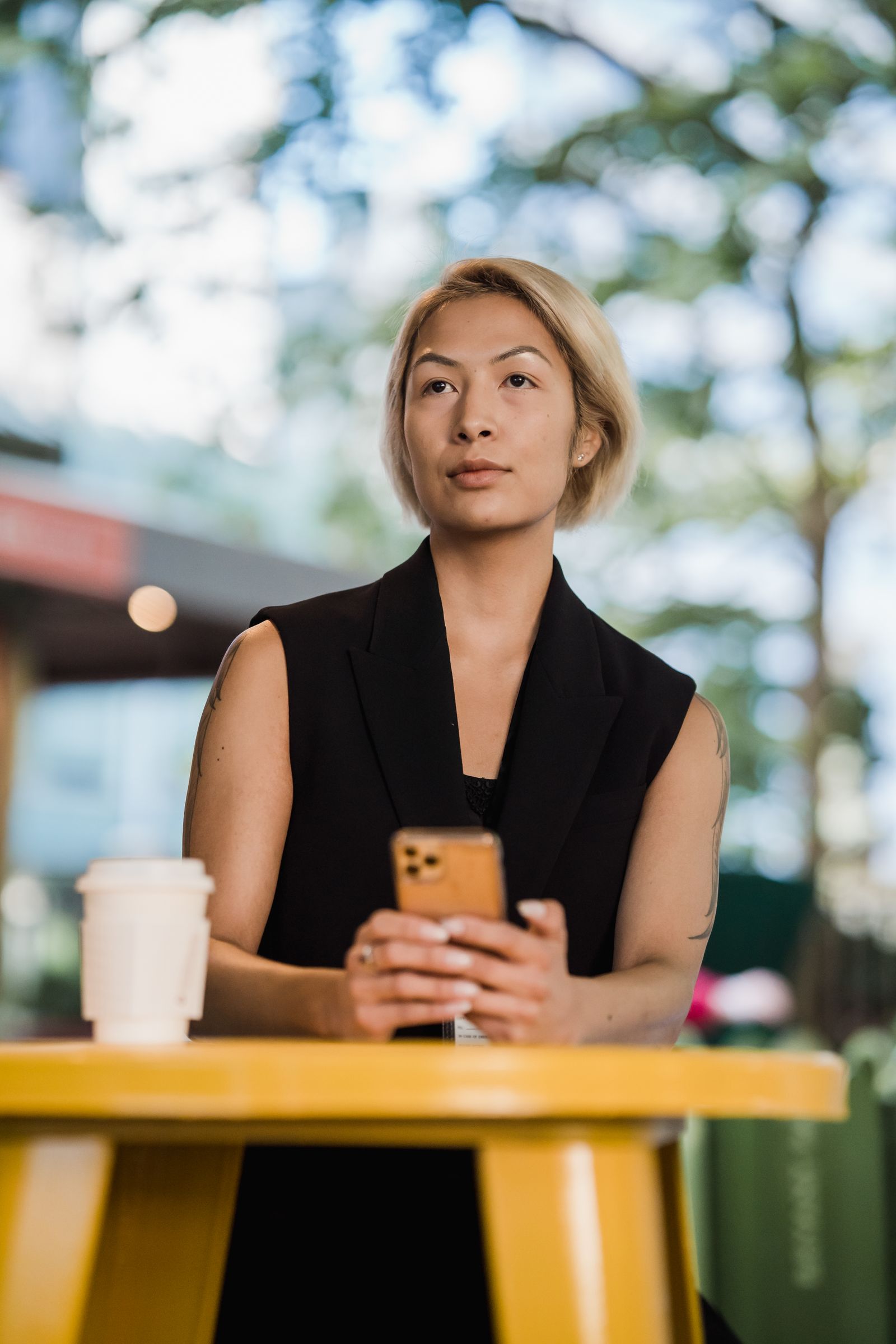 A young professional at a café table, messaging on WhatsApp the way Sara — Café Nejma's typical customer — would